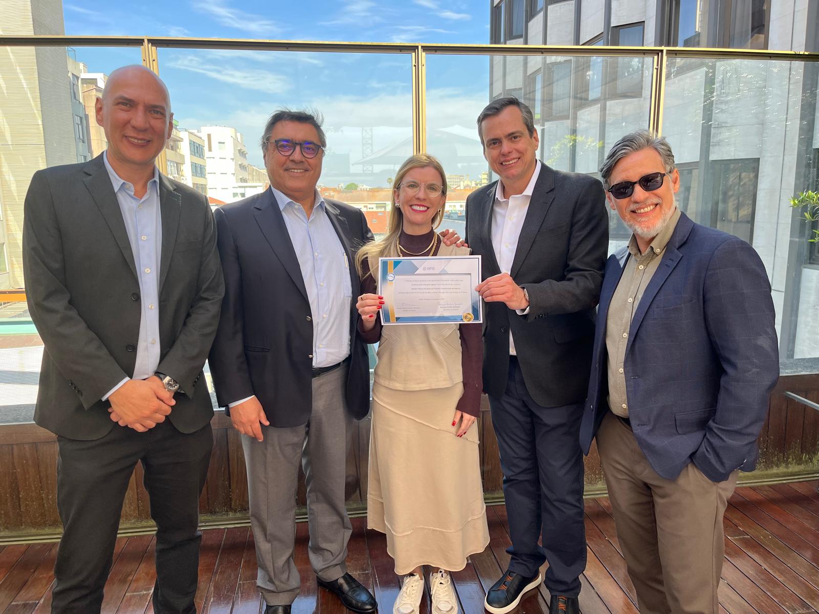 Letícia exibe o diploma do curso ao lado dos palestrantes convidados e organizadores da imersão, no rooftop da MDS, no Porto, em Portugal